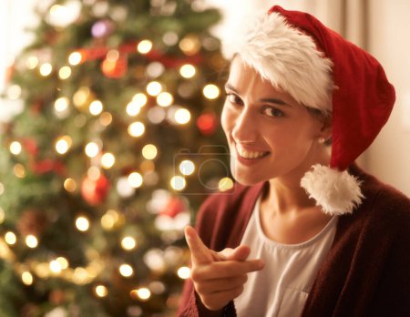 Christmas, portrait or woman for finger, warning or naughty in playful break in festive season. Gen z female person, red hat or smile to hey you, no or humor to relax in living room, tree and lights.