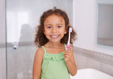 Foto de Retrato, sonrisa y niña cepillándose los dientes en un baño para el cuidado dental, de bienestar u oral en su casa. Feliz, cara y niño en una casa con cepillo de dientes para limpieza bucal, desarrollo infantil o aprendizaje. - Imagen libre de derechos