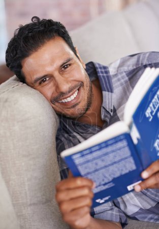 Photo for Man, portrait and reading a book for knowledge in home, literature and information. Happy male person, story and fiction novel for education in living room on weekend, comfortable and relax on sofa. - Royalty Free Image