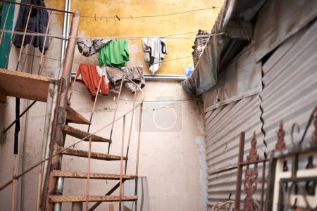 Escaliers, maison extérieure et en acier avec de la rouille en matériau zinc avec des ordures dans un établissement informel ou un quartier au Brésil. Maison, quartier résidentiel et communauté avec immeuble ancien ou bidonville en lieu urbain.