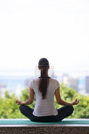 Photo for Woman, meditation and yoga with mat by window for workout, exercise or spiritual wellness at home. Rear view of female person or yogi meditating in relax for inner peace, zen or fitness at the house. - Royalty Free Image