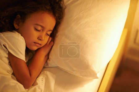 Photo for Child, sleeping and peace in bed at night, comfortable and tired or dream on pillow in home. Female person, girl and resting in bedroom or lying to relax, exhausted and fatigue or blanket for calm. - Royalty Free Image