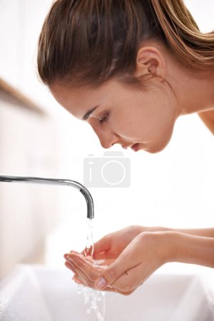Photo for Woman, house and hygeine for washing face, skincare and sink in self care and beauty with smile in restroom. Female person, clean water and tap in bathroom, morning and happy for health at home. - Royalty Free Image