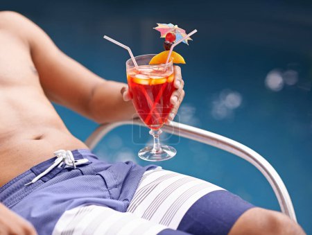 Téléchargez les photos : Homme, se détendre et boire à la piscine avec cocktail à l'hôtel, station balnéaire et Voyage en vacances de luxe. Été, vacances et verre d'alcool à portée de main sur le pont au bord de la piscine à Miami avec l'hospitalité en gros plan. - en image libre de droit
