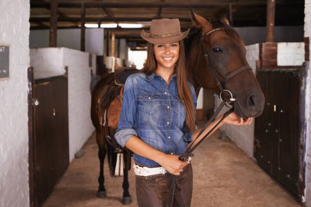 Téléchargez les photos : Cowgirl, portrait et femme heureuse avec cheval à la grange ou écurie au Texas pour les loisirs. Chapeau occidental, personne et animal au ranch avec animal de compagnie, bétail ou étalon pour passe-temps avec soin à la ferme équestre. - en image libre de droit