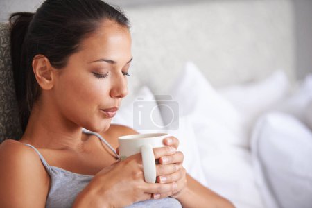 Photo for Woman, coffee and bed for relax in morning for wakeup and drink in cup for warm and steam with pillow. Young person with beverage for blow caffeine on weekend for boost in mug with pajamas. - Royalty Free Image