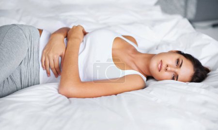 Photo for Woman, stomach ache and pain in bed with virus, menstruation cramps or endometriosis. Gut health crisis, colon blockage or constipation with bloating from stress, PMS or IBS with appendicitis at home. - Royalty Free Image