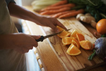 Photo for Closeup, kitchen and fruits with hands, orange or wood board with knife, vegetables or salad. Person, vegan or chef with utensils or ingredients for lunch or supper with healthy meal, home or dinner. - Royalty Free Image