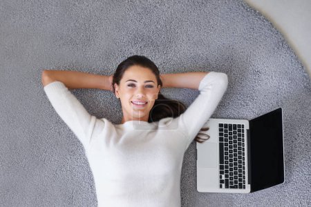 Photo for Happy woman, relax and lying with laptop above on floor for break, rest or research at home. Top view of female person or freelancer with smile, computer or thinking on rug and mockup screen at house. - Royalty Free Image