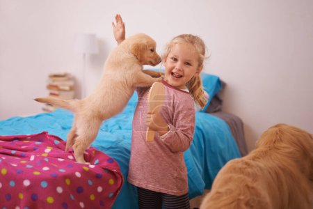 Photo for Girl, child and puppy with portrait on bed for playing, bonding and protection in bedroom of home with brush. Kid, golden retriever and dog for companion, affection and embrace with care in apartment. - Royalty Free Image