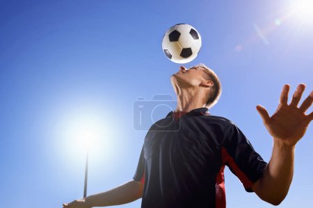 Photo for Football, bounce and head with man, game and training with competition, sunshine and exercise. Blue sky, lens flare and player with practice or athlete with skills or technique with fitness or soccer. - Royalty Free Image
