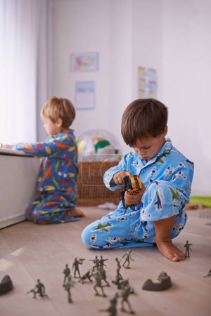 Foto de Niños, juguetes y niños pequeños en pijama jugando por diversión con figuras de acción, coche o juegos. Hermanos, desarrollo infantil y niños pequeños se unen en la sala de juegos para aprender en el hogar familiar - Imagen libre de derechos