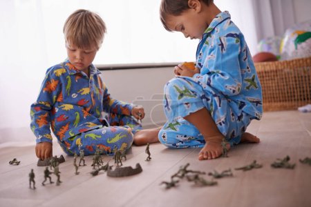 Jungen, spielende und Kinder im Schlafanzug mit Spielzeug zum Spaß mit Actionfiguren, Auto oder Spielen. Brüder, die Entwicklung des Kindes und die Bindung der kleinen Kinder im Spielzimmer für das Lernen zu Hause der Familie