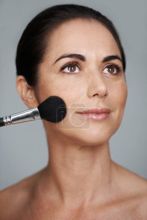 Photo for Cosmetics, brush and mature woman in studio with beauty, natural and facial glow routine. Makeup, self care and confident female person with cosmetology tool for glow isolated by gray background - Royalty Free Image
