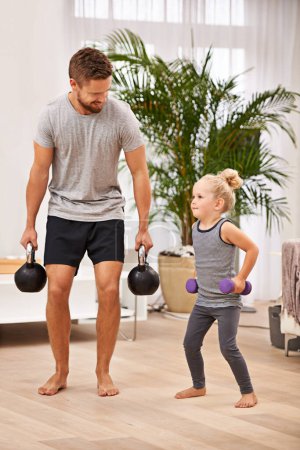 Photo for Man, girl kid and weightlifting for fitness, father and daughter spending time together for love in living room. Dumbbells, kettlebell and muscle training with exercise and bonding at family home. - Royalty Free Image