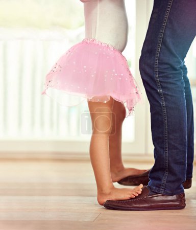 Photo for Legs, feet with father and child dancing, teaching and learn with music and rhythm at family home. Man, young girl and standing together with activity for bonding, ballet with safety and support. - Royalty Free Image