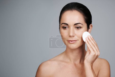 Photo for Mature woman, pad and cleanse in studio, skin care and facial treatment on gray background. Female person, cotton and swab for grooming in daily routine, mockup space and dermatology to remove makeup. - Royalty Free Image