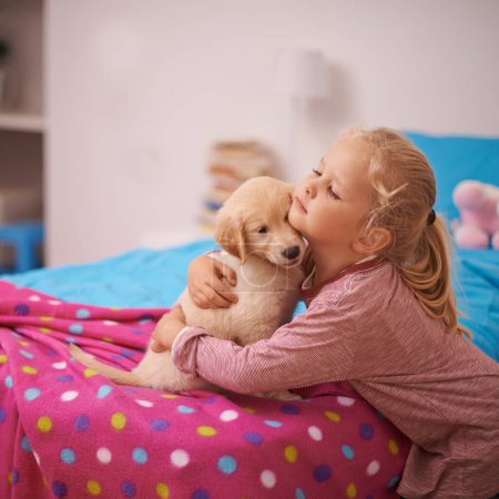 Photo for Girl, child and puppy with hug on bed for playing, bonding and protection in bedroom of home with love. Kid, golden retriever and dog for companion, affection and embrace with pet care in apartment. - Royalty Free Image