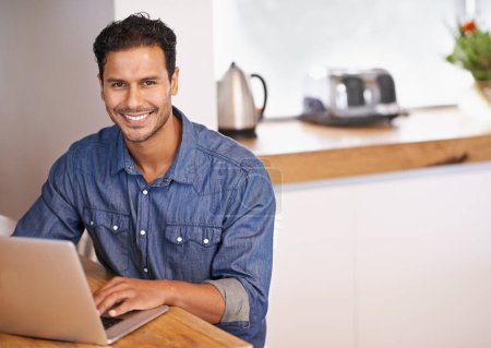 Photo for Website, research and internet for man with laptop on table in kitchen for online, web and info for work. Entrepreneur or freelancer and smile with keyboard for tech, typing and email with mockup. - Royalty Free Image