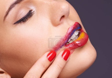 Photo for Lipstick, smear and woman with makeup and hand, beauty and red nail polish with cosmetic product in studio. Face, smudge on skin and color for cosmetology with manicure and art on purple background. - Royalty Free Image
