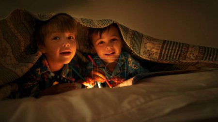 Photo for Blanket, flashlight and children at night with happiness in portrait with drawing in a book. Friends, relax and sketch on notebook in dark with light or torch under duvet at sleepover in pillow tent. - Royalty Free Image