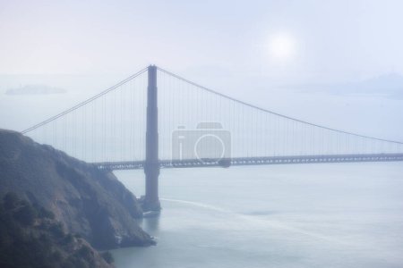 Photo for Golden Gate bridge, fog and ocean at sunrise by road, infrastructure or architecture in nature. Street, highway and hill with rocks, sea or horizon in morning sunshine for transport in San Francisco. - Royalty Free Image