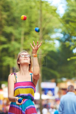 Téléchargez les photos : Camping, festival et jongler avec la femme dans le parc pour l'événement, la fête ou la célébration dans l'environnement d'été. Nature, forêt ou bois avec des jeunes à lunettes jonglant avec des balles en plein air lors d'un rassemblement social. - en image libre de droit