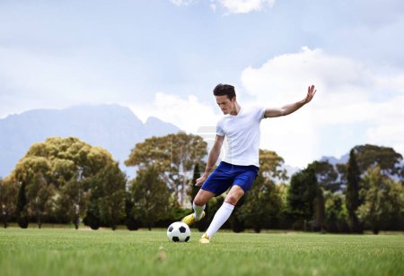 Man, soccer player and shooting with ball on field with power, speed and aim at target in training for club. Person, football and sport with kick exercise and workout for wellness, fitness and game.