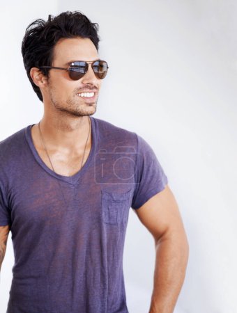 Photo for Happy, man and fashion with sunglasses on wall outdoor with confidence, cool style and pride. Summer, holiday and person smile in casual outfit for vacation, break and relax on white background. - Royalty Free Image