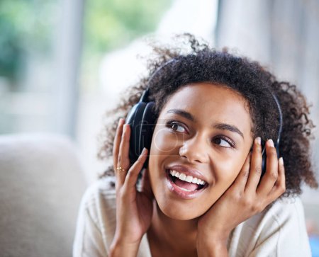 Kopfhörer, Lächeln und eine glückliche Frau auf der Couch, im Wohnzimmer und beim Musikhören. Glücklich, freudig oder nachdenkend beim Streamen von Audio, Podcast oder Radio zur Unterhaltung für afrikanische Hörerinnen.