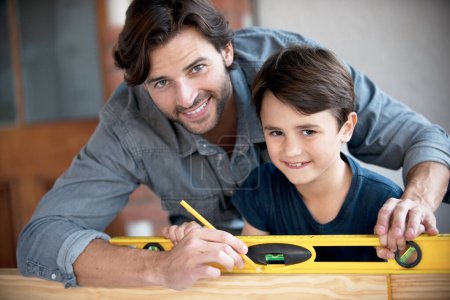 Photo for Father, kid and woodwork at home for portrait, bonding and building with safety gear. Dad, son and carpenter for renovating, measuring and teaching moment for development of house with construction. - Royalty Free Image