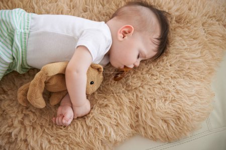 Photo for Toddler, sleep and home with teddybear in sofa to rest, tired and relax with dummy and dream. High angle, baby, and nap in couch for child development, growth and innocent with peace for bedtime - Royalty Free Image