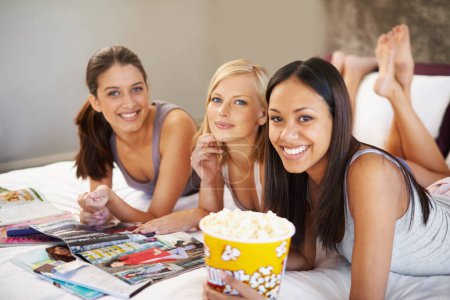 Photo for Friends, popcorn and portrait for sleepover, social and bedroom for bonding and excited group for snacks. Female people, together and magazines for jokes, besties and entertainment with conversation. - Royalty Free Image