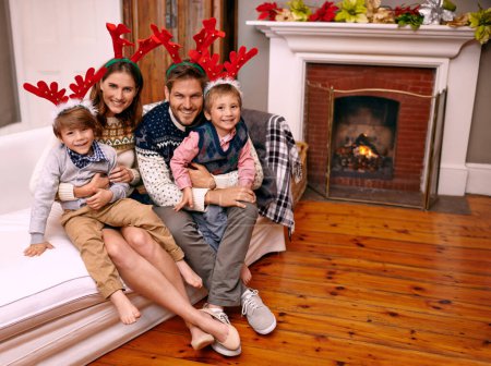 Photo for Christmas, portrait and happy family on sofa in home for holiday or festive celebration. Xmas, parents and smile of children in living room with antlers, bonding and kids together at party in house. - Royalty Free Image