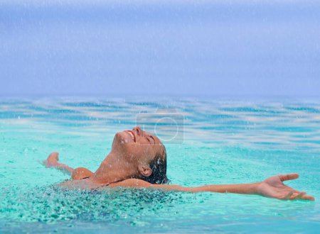 Photo for Face, freedom and rain with woman in swimming pool for travel, holiday or vacation as tourist. Relax, smile and wet in water with happy young swimmer person outdoor at tropical resort for getaway. - Royalty Free Image