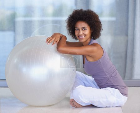 Photo for Woman, portrait and exercise ball for fitness and wellness in studio or home for balance and health on the floor. Happy and young African person with workout, pilates and relax on ground for break. - Royalty Free Image