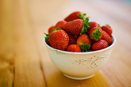 Photo for Food, health and strawberry bowl in kitchen of home, on wooden counter top for diet or nutrition. Fruit, wellness and lose weight with berries on surface in apartment for detox, minerals or vitamins. - Royalty Free Image