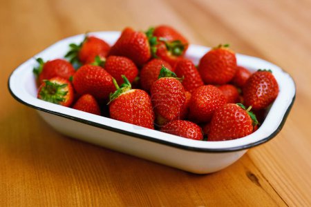 Photo for Fruit, health and strawberry bowl in kitchen of home, on wooden counter top for diet or nutrition. Food, wellness and lose weight with berries on surface in apartment for detox, minerals or vitamins. - Royalty Free Image