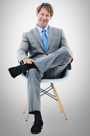 Téléchargez les photos : Homme d'affaires, portrait et assis avec chaise dans la détente pour une entrevue ou une possibilité de carrière sur un fond de studio gris. Homme ou employé avec sourire dans la mode, le style ou le travail pour le démarrage sur l'espace de maquette. - en image libre de droit