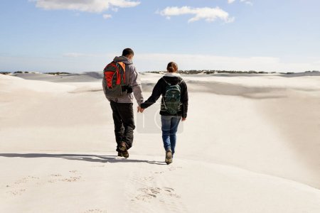 Photo for Backpack, travel or couple in desert holding hands for adventure, journey or resort, location or explore. Freedom, love or back of people in Egypt for sand dunes walking, wellness or hiking in nature. - Royalty Free Image