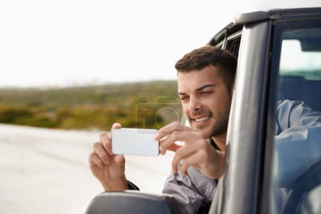 Photo for Road trip, man and cellphone for photography in car, game route and sightseeing for driving for journey. Person, traveller and exploration on holiday in nature, street and leisure in vehicle in oman. - Royalty Free Image