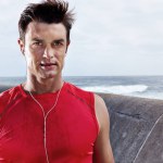 Outside, male runner and face with earphones, outdoors and seaside for exercise routine. Fitness, sport and marathon for active man, listening and enjoying radio for motivation, mindset and running.