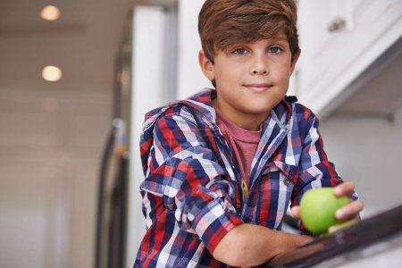 Photo for Portrait, apple and boy kid in kitchen of home with food as diet, health or nutrition for development. Fruit, wellness and organic snack with confident teen child in apartment for growth or hunger. - Royalty Free Image