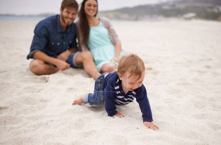 Téléchargez les photos : Heureux, bébé et parents sur la plage dans le sable, l'été et le plaisir en famille avec l'enfant rampant. Rire, sourire et couple avec un enfant en vacances ensemble pour le développement de la relation et le plaisir de la nature en mer. - en image libre de droit