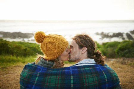 Photo for Happy couple, kiss and bonding together in nature, blanket and romantic getaway with camping by ocean. Man, woman or love on vacation on weekend break, cape town or travel adventure by sea in sunset. - Royalty Free Image