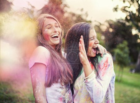 Foto de Feliz, pintura en polvo y las amigas se ríen al aire libre con el festival Holi y evento colorido con sonrisa. Celebración, amor y emoción en la naturaleza con los jóvenes y polvo de color loco para la fiesta juntos. - Imagen libre de derechos