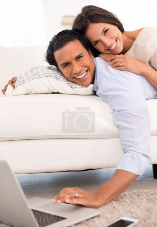 Téléchargez les photos : Couple, portrait et ordinateur portable sur le canapé dans le salon pour regarder des films, défiler et coller ensemble à la maison. Détendez-vous, homme et femme couchés sur le canapé dans le salon avec la technologie pour le streaming en ligne - en image libre de droit