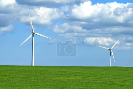 Photo for Wind turbine, grass and sky with clouds for nature in environment and outdoor for landscape and energy. Sustainability, weather and season with ecology for farm and field in agriculture and industry. - Royalty Free Image