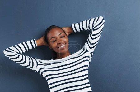 Téléchargez les photos : Femme noire, heureuse et les yeux fermés en studio pour se détendre, la paix et la mode top par fond bleu. Étudiant africain, pause et repos sur les mains pour l'éducation, le bien-être et la génération positive z avec des vêtements funky. - en image libre de droit