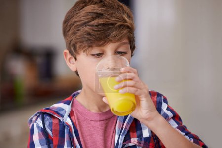 Photo for Kids, kitchen and boy drinking orange juice from glass in morning for diet, health or nutrition. Breakfast, children and cup with young teen in apartment to enjoy fresh beverage for development. - Royalty Free Image